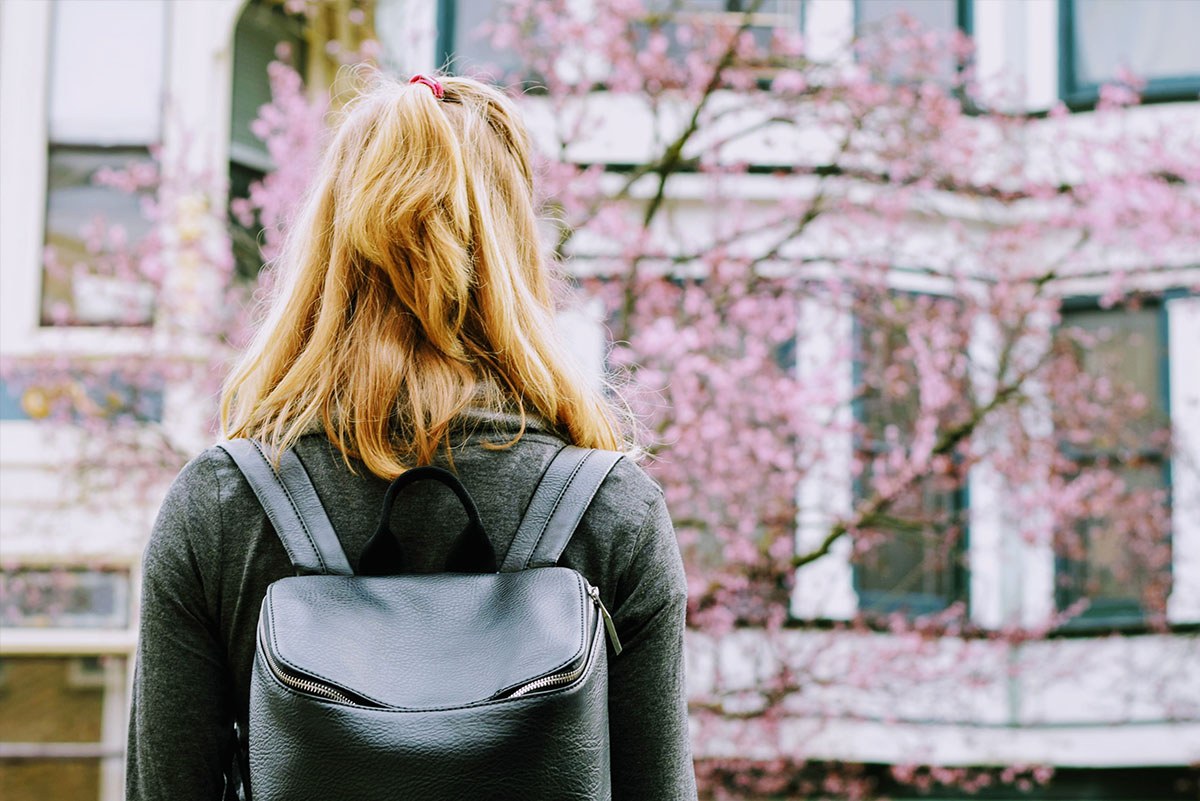 Student Standing Outside In Front Of A Tree Thinking About Her Upcoming School Year